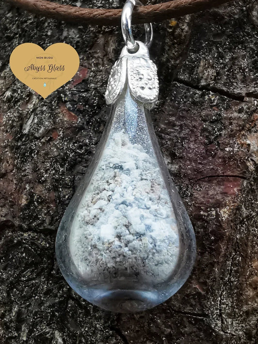 Bijou funéraire en verre soufflé renfermant des cendres, vu de près