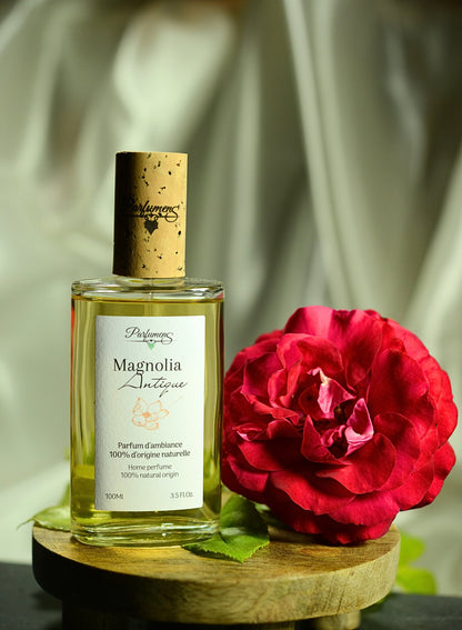 Magnolia Antique, parfum d'ambiance naturel Parfumens, flacon de 100 ml à côté d'une fleur rouge