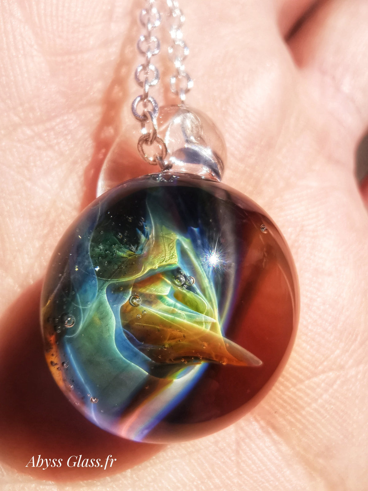 Pendentif en verre soufflé à la flamme de la collection Univers, posé dans la main